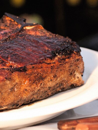 A juicy steak on a white plate, perfectly grilled. A glass of red wine is beside it. | © Steak Boutique