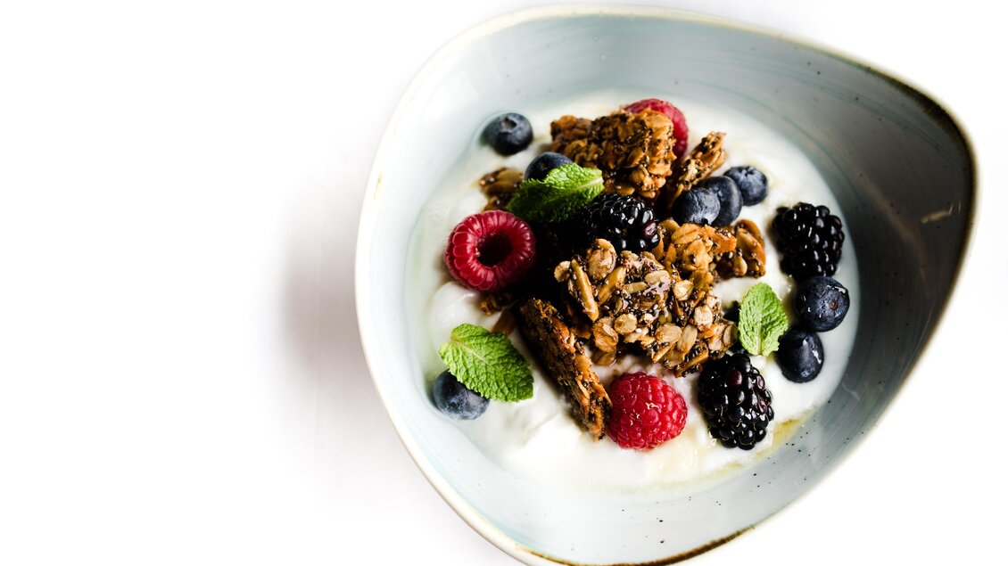 Eine Schüssel Joghurt mit einer Mischung aus frischen Beeren und Granola. Minzblätter verleihen dem Gericht eine frische Note. | © Steffl-Bäck Sebastian Knapp
