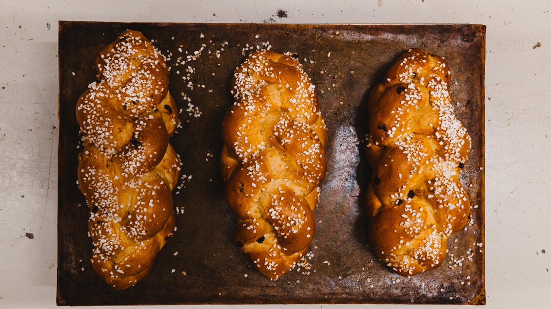 Drei frisch gebackene Hefezöpfe auf einem Blech. Sie sind goldbraun und mit Puderzucker bestreut. | © Steffl-Bäck Sebastian Knapp