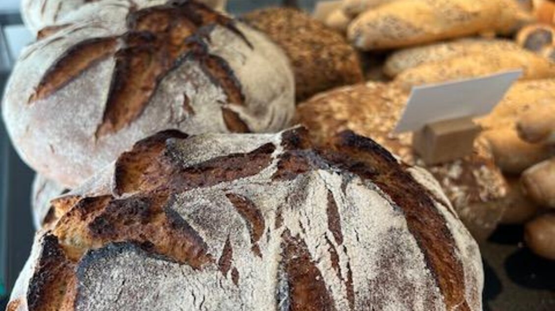 Frisches, knuspriges Brot mit einer goldbraunen Kruste. Im Hintergrund sind weitere Brote und eine gemütliche Verkaufsumgebung zu sehen. | © Steffl-Bäck Sebastian Knapp e.U.