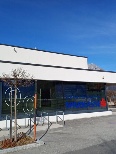 A modern building with large windows and clean lines. In the front, there are colorful numbers and a blue inscription. | © Heidi Grundner