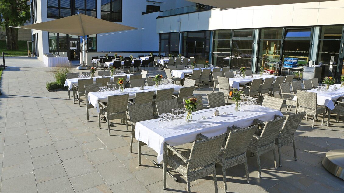 Eine elegante Terrasse mit mehreren gedeckten Tischen. Der Bereich ist gut beleuchtet und lädt zu einer Feier im Freien ein. | © Steiermarkhof - Foto Pachernegg