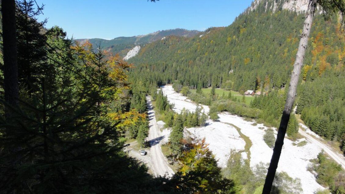 Eine malerische Berglandschaft mit dichten Wäldern und klaren Wasserläufen. Im Hintergrund sind sanfte Hügel und ein strahlend blauer Himmel zu sehen. | © M. Ressel