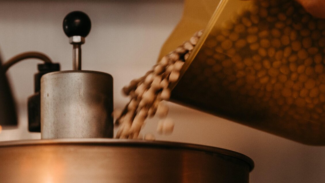 Eine Hand kippt eine Tüte mit Erbsen in einen metallischen Behälter. Der Behälter hat einen kleinen Hebel und steht auf einer Arbeitsfläche. | © Region Graz - Mias Photoart