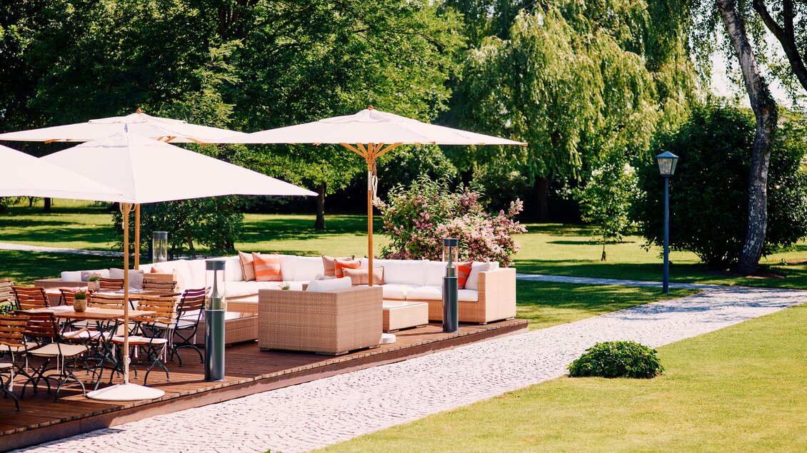 Ein einladender Außenbereich mit gemütlichen Möbeln und Sonnenschirmen. Umgeben von üppigem Grün und Pflanzen, perfekt zum Entspannen. | © Steirerschlössl