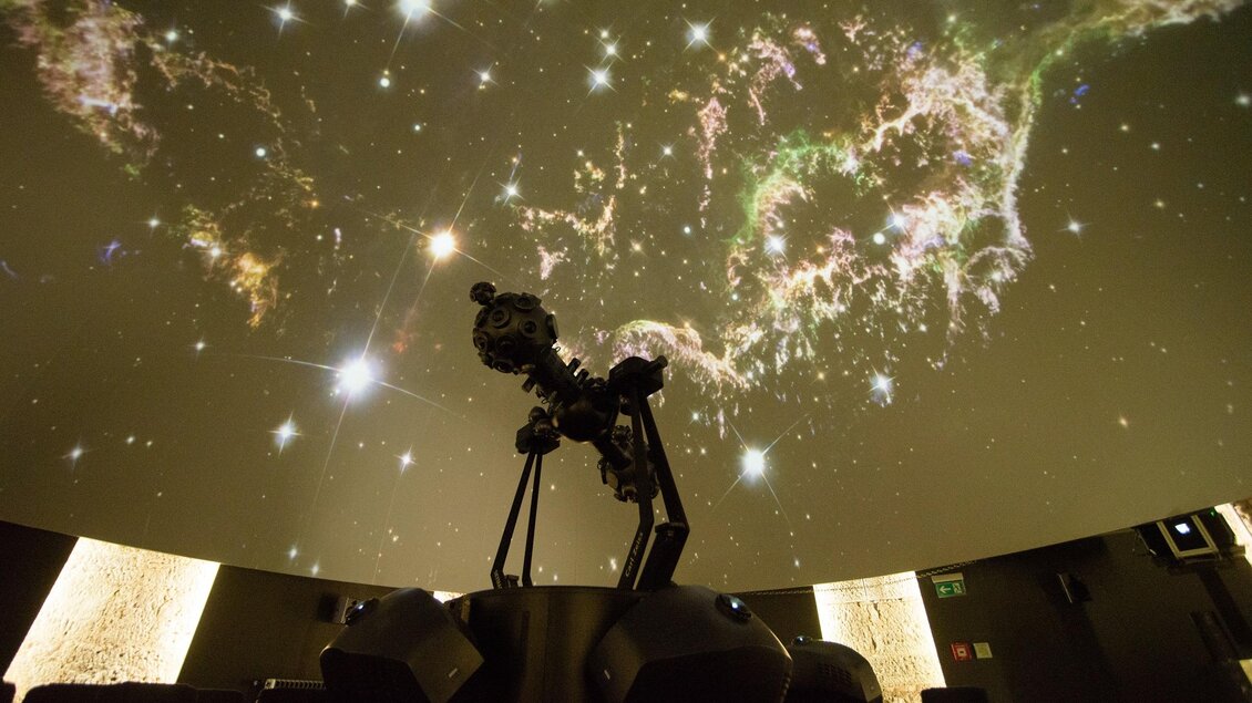 Ein Planetarium mit einem Star-Projektor im Vordergrund. Der Himmel ist mit Sternen und Nebeln beleuchtet. | © Foto Mitteregger
