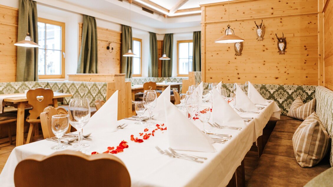 Ein gemütliches Restaurant mit Holzdekor und stilvoll gedeckten Tischen. Die Dekoration umfasst Servietten und Blütenblätter auf dem Tisch. | © Hotel Restaurant Stockinger