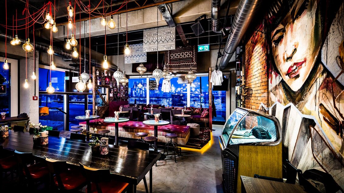 Ein stilvolles Restaurant mit moderner Ausstattung und gemaltem Wandbild. Die Atmosphäre ist gemütlich mit warmem Licht und modernen Möbeln. | © Streets - Werner Krug