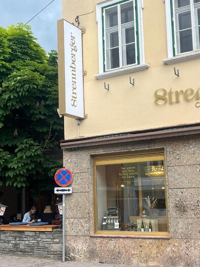 A café and bistro named "Streanberger" with large windows and a green tree front. The facade is designed to be friendly and welcoming. | © TVB Ausseerland Salzkammergut_ Nathalie Schickinger