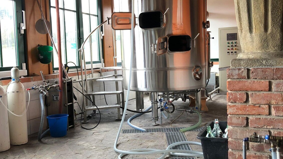 Eine moderne Brauanlage in einem hellen Raum. Der Fokus liegt auf dem großen, silbernen Gärtank und den dazugehörigen Geräten. | © Stubalmbräu-Mara