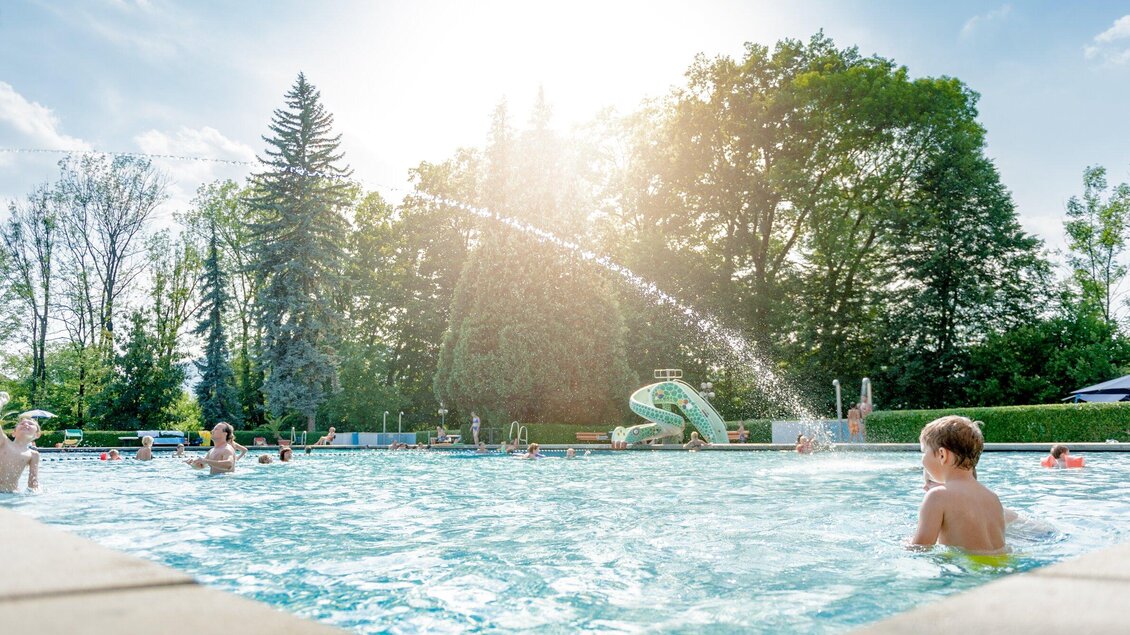 Im Kinderbecken Stukitzbad herrscht reges treiben. Im Hintergrund sind Bäume und eine Wasserrutsche zu sehen. | © Holding Graz - Joel Kernasenko