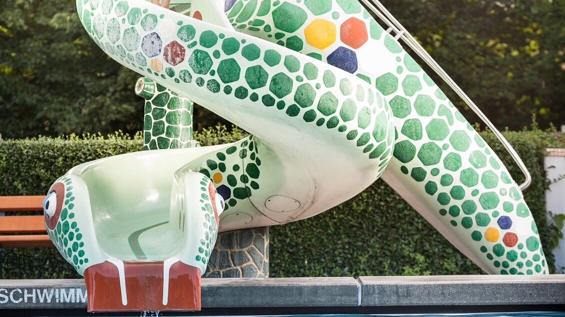 Die farbenfrohe Wasserrutsche in Form einer Schlange im Stukitzbad. Sie ist mit bunten Kacheln verziert und führt ins Kinderbecken. | © Holding Graz - Joel Kernasenko