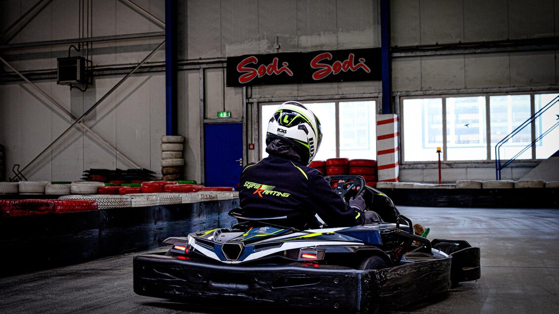 Ein Fahrer in einem Go-Kart auf einer Indoor-Bahn. Im Hintergrund sind Reifen und eine Wand mit dem Schriftzug "Sodi" zu sehen. | © TV Region Graz - Mias Photoart