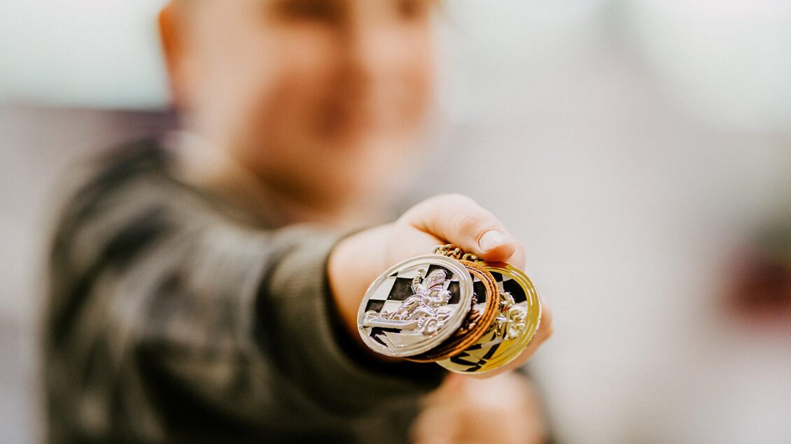 Ein Junge hält stolz eine Medaille in der Hand. Die Medaille ist glänzend und zeigt ein sportliches Motiv. | © TV Region Graz - Mias Photoart
