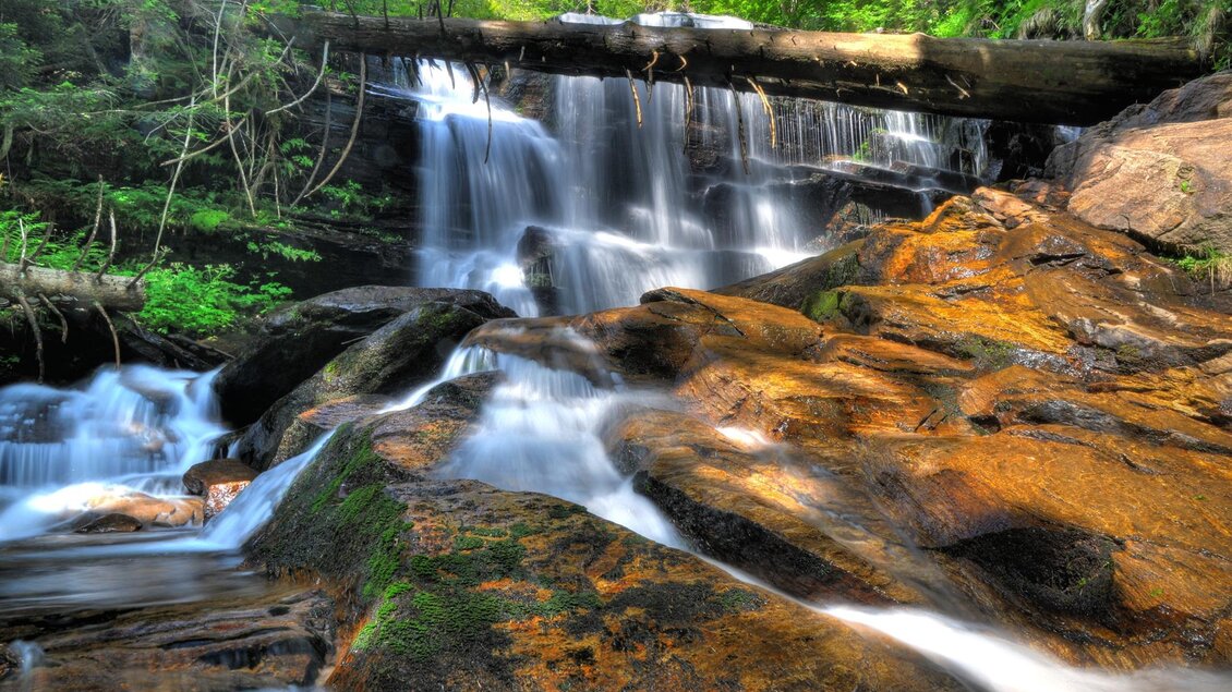 Ein schöner Wasserfall fließt über große, glatte Felsen. Die Umgebung ist grün und üppig, mit viel natürlichem Licht. | © Sulmwasserfall