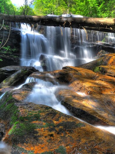 A beautiful waterfall flows over large, smooth rocks. The surroundings are green and lush, with plenty of natural light. | © Sulmwasserfall