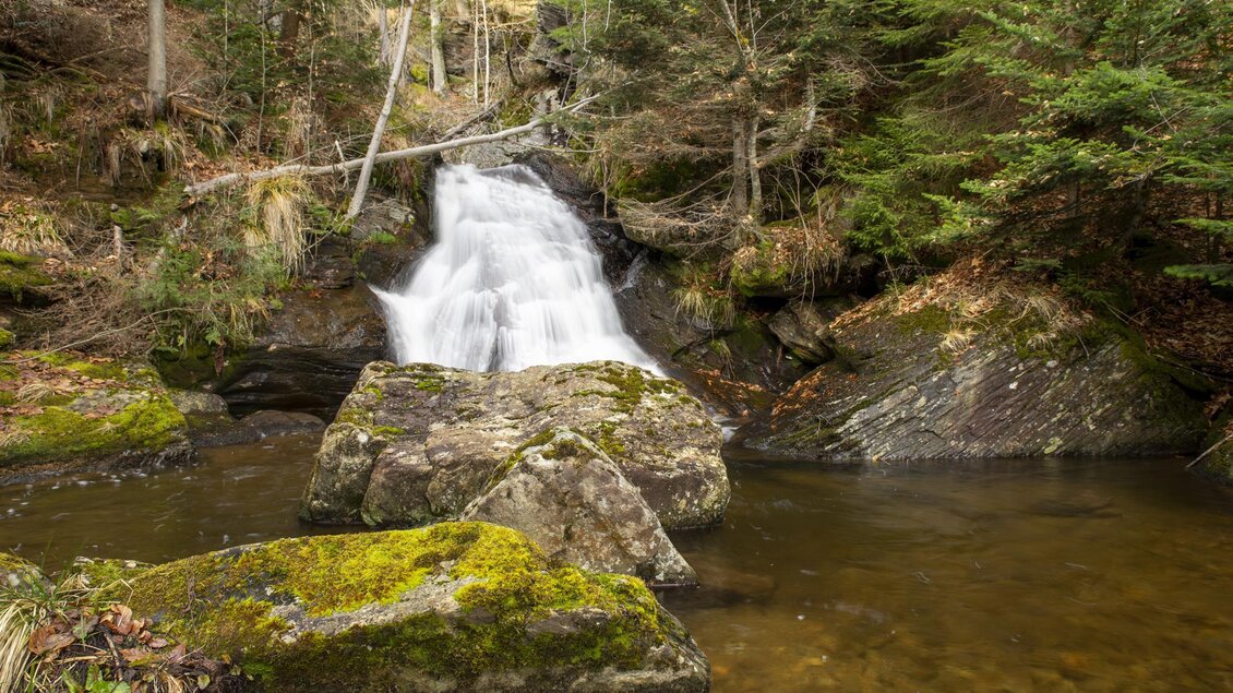 Ein schöner Wasserfall fließt über große Steine in einen klaren Teich. Umgeben von grünen Bäumen und natürlicher Vegetation vermittelt die Szene Ruhe und Frieden. | © Sulmwasserfall