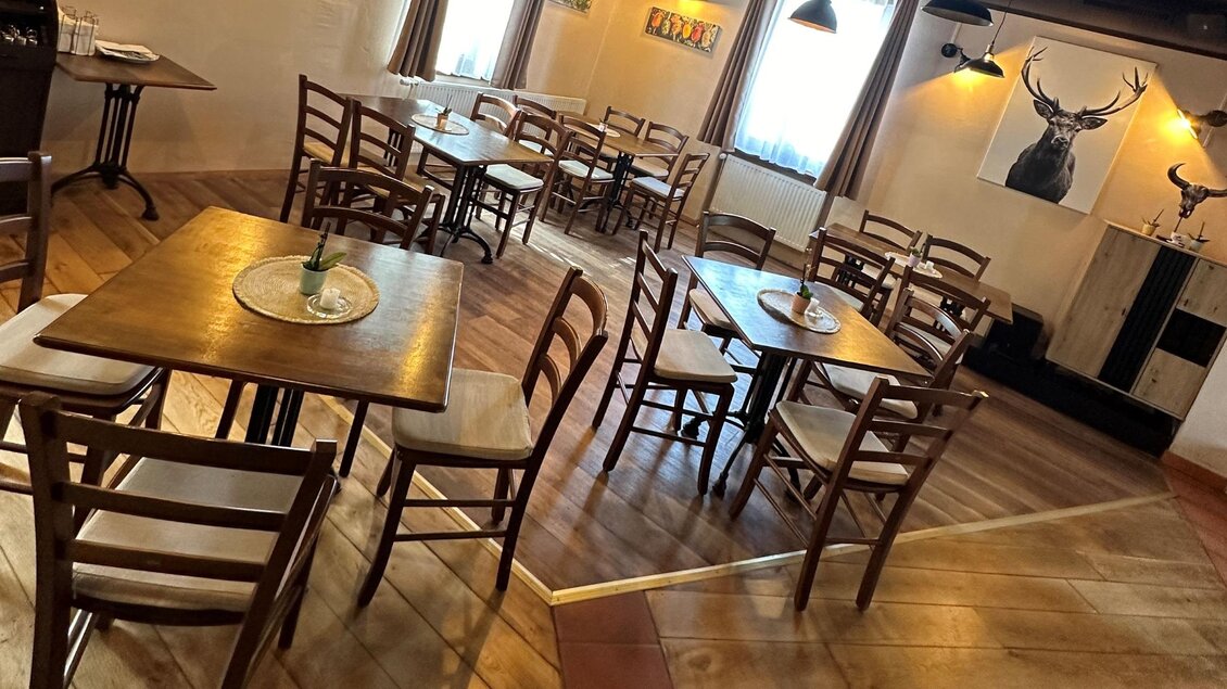 Ein gemütliches Restaurant mit Holztischen und Stühlen. Die Wände sind hell, und es gibt sanfte Beleuchtung sowie dekorative Elemente. | © TREND