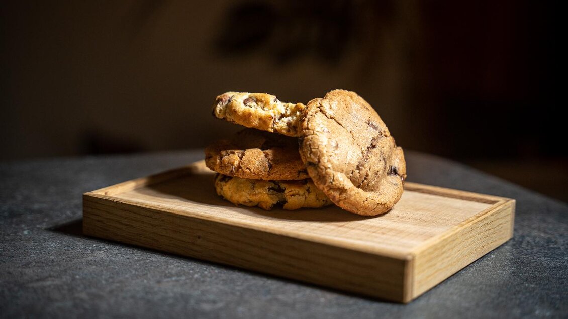 Ein Stapel köstlicher Kekse liegt auf einem Holzbrett. Die Kekse sind goldbraun und haben Schokoladenstückchen.