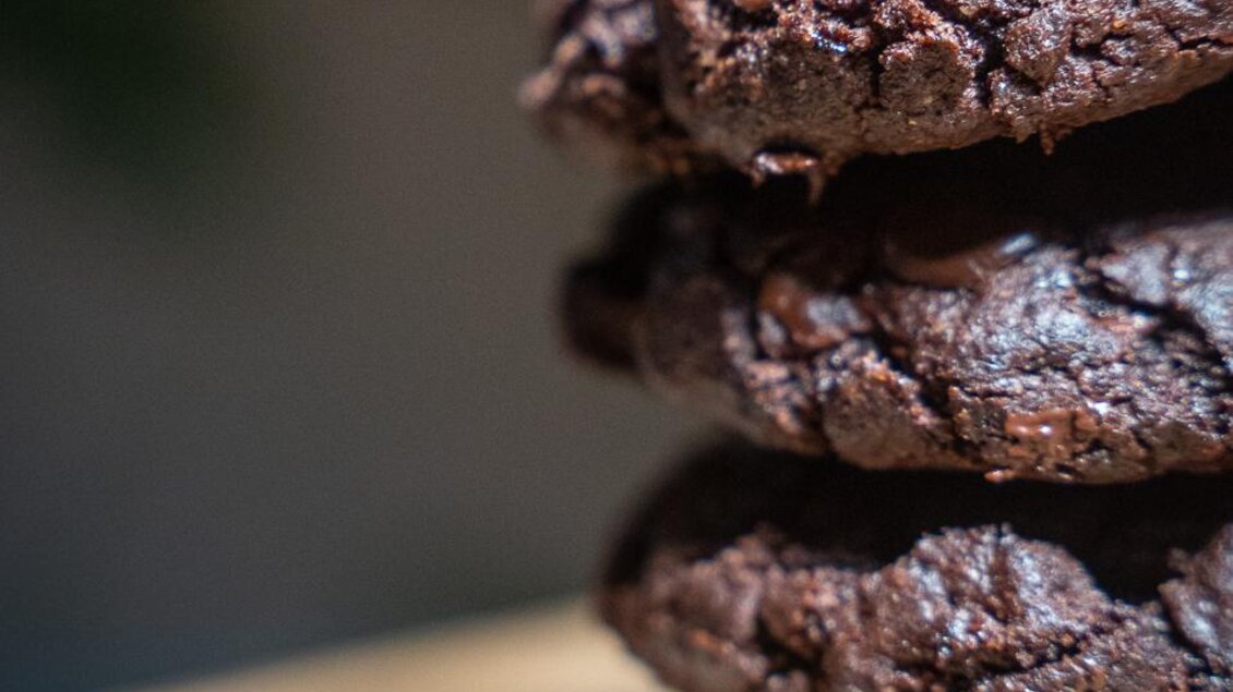 Ein Stapel köstlicher Schokoladenkekse auf einem Holzbrett. Die Kekse sind frisch gebacken und laden zum Genießen ein.