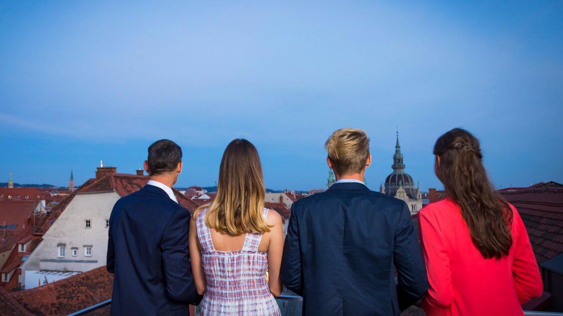 Vier Personen genießen vom Tagescafé Freiblick Graz den Panorama-Ausblick über die Dächer von Graz und den Dom | © Graz Tourismus - Werner Krug