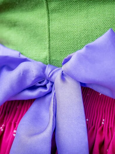 Ein bunter Trachtenrock mit einem lila Schleifenband. Der Rock hat eine pinke Farbe und eine strukturierte grüne Oberseite. | © www.narzissenfest.at_Christine Struz