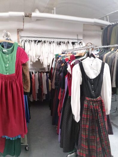 Ein Geschäft mit traditionellen Kleidern, die an Kleiderständern hängen. Die Kleidung ist bunt und zeigt verschiedene Stile und Muster. | © Erika Baumann