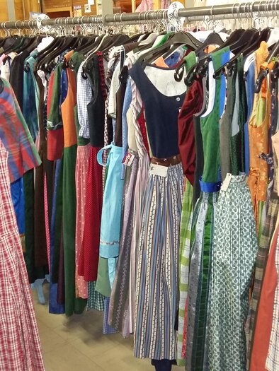 A clothing rack with a variety of colorful dresses. In the foreground, a checkered dress can be seen, while additional models hang in the background. | © Kirchschllager Petra