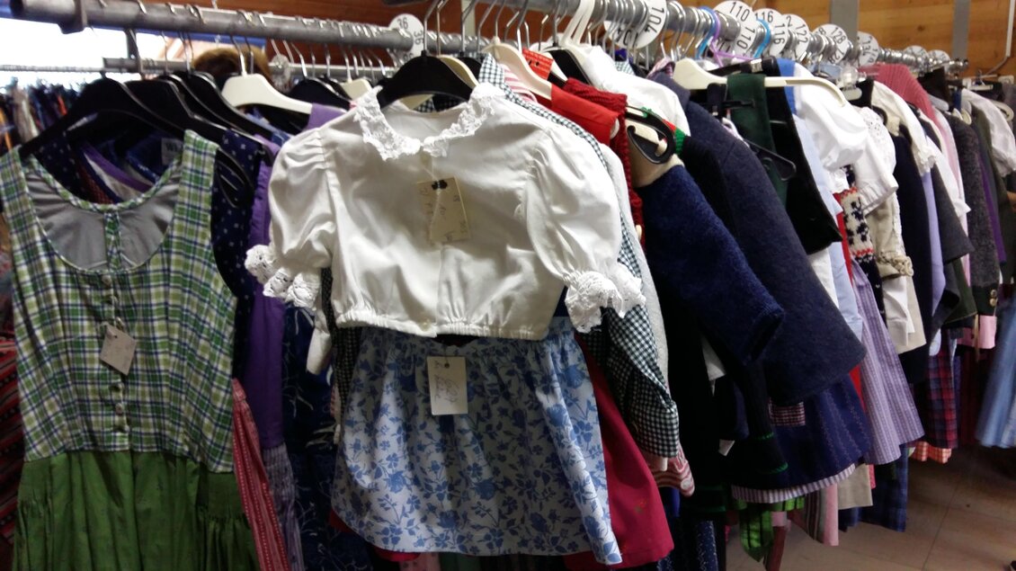 Eine Auswahl an traditionellen Trachtenkleidern hängt an Garderoben. Die Kleider sind bunt und variieren in Stil und Muster. | © Kirchschlager Petra
