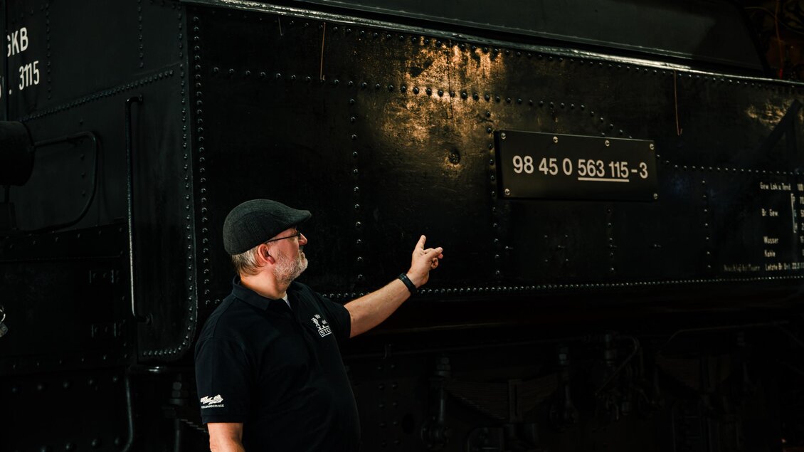 Bei einer Führung im technischen Eisenbahnmuseum Lieboch zeigt der Mann auf die Nummern einer Dampflok. Diese Zahlen geben Auskunft über das Baujahr und einige technische Details. | © Mias Photoart