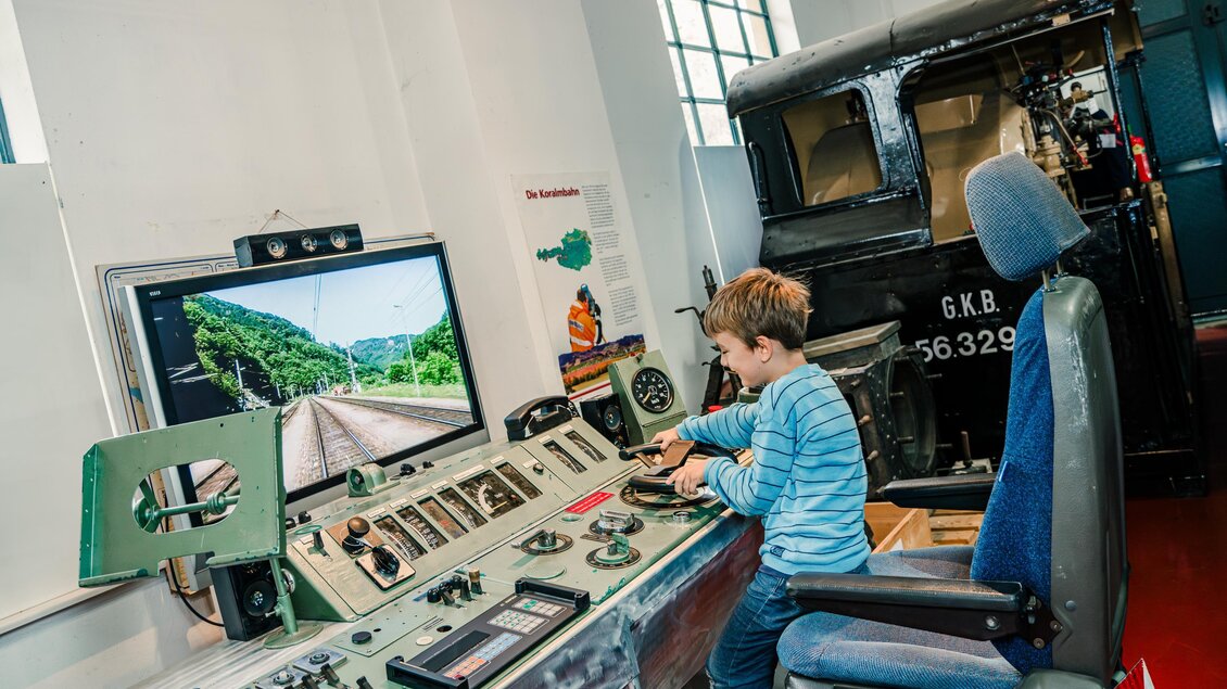 Ein Junge sitzt an einem Steuerpult eines Zugsimulators im technischen Eisenbahnmuseum Lieboch. Hier können Zugfahrten nachgestellt werden, die Landschaft wirkt sehr real.  | © Mias Photoart