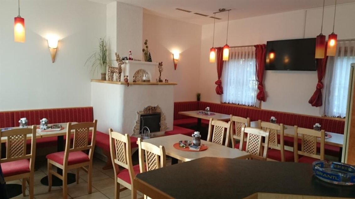 Ein gemütliches Restaurant mit rot gepolsterten Bänken und Holztischen. Die sanfte Beleuchtung und die Dekoration schaffen eine einladende Atmosphäre. | © Muhri & Platz OG;