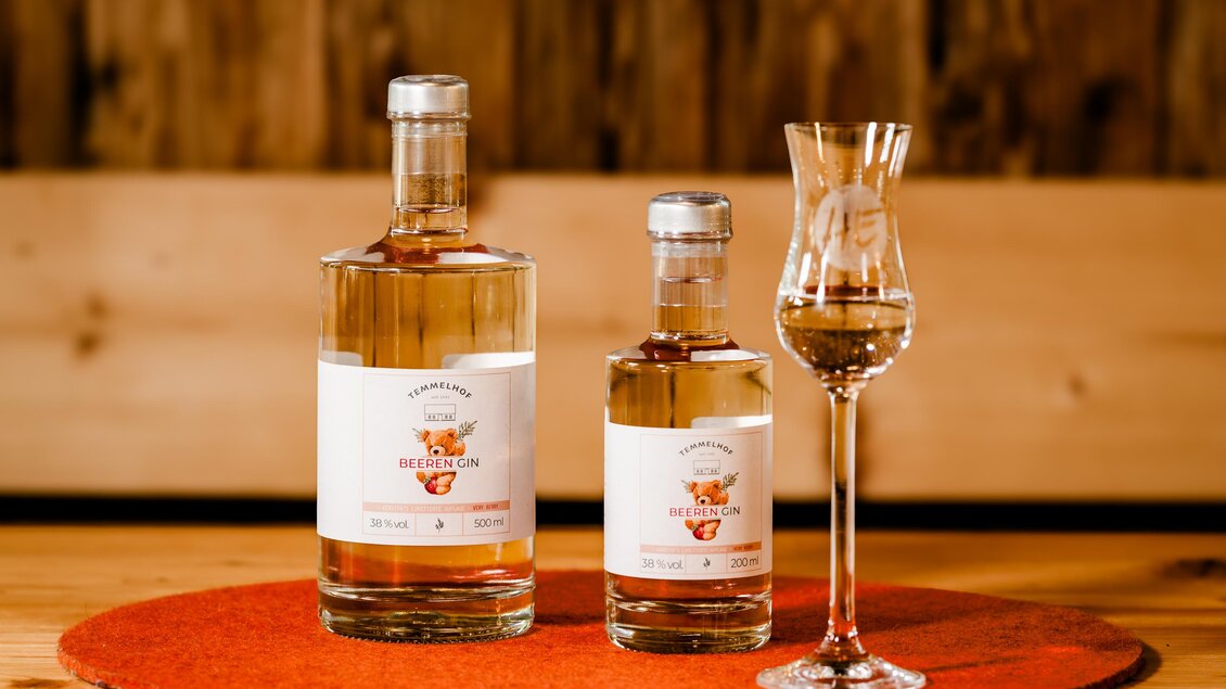 Zwei Flaschen Likör und ein Glas auf einem runden Untersetzer. Der Hintergrund ist aus Holz und vermittelt eine rustikale Atmosphäre. | © Region Graz -  Mias Photoart