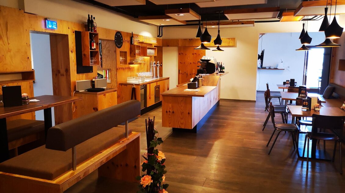 Ein modernes Café mit Holzinterieur und stilvollen Lampen. Die gemütlichen Sitzbereiche laden zum Verweilen ein. | © Kerim Sijercic