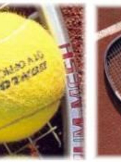 A yellow tennis ball lies on a tennis court next to a racket with more balls. The court features a distinctive terracotta surface.