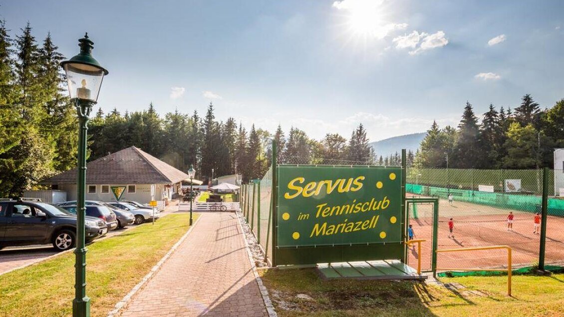 Ein Tennisclub in Mariazell mit grünen Plätzen und Wald im Hintergrund. Die sonnige Atmosphäre lädt zu sportlichen Aktivitäten ein. | © www.mariazell.blog | Fred Lindmoser