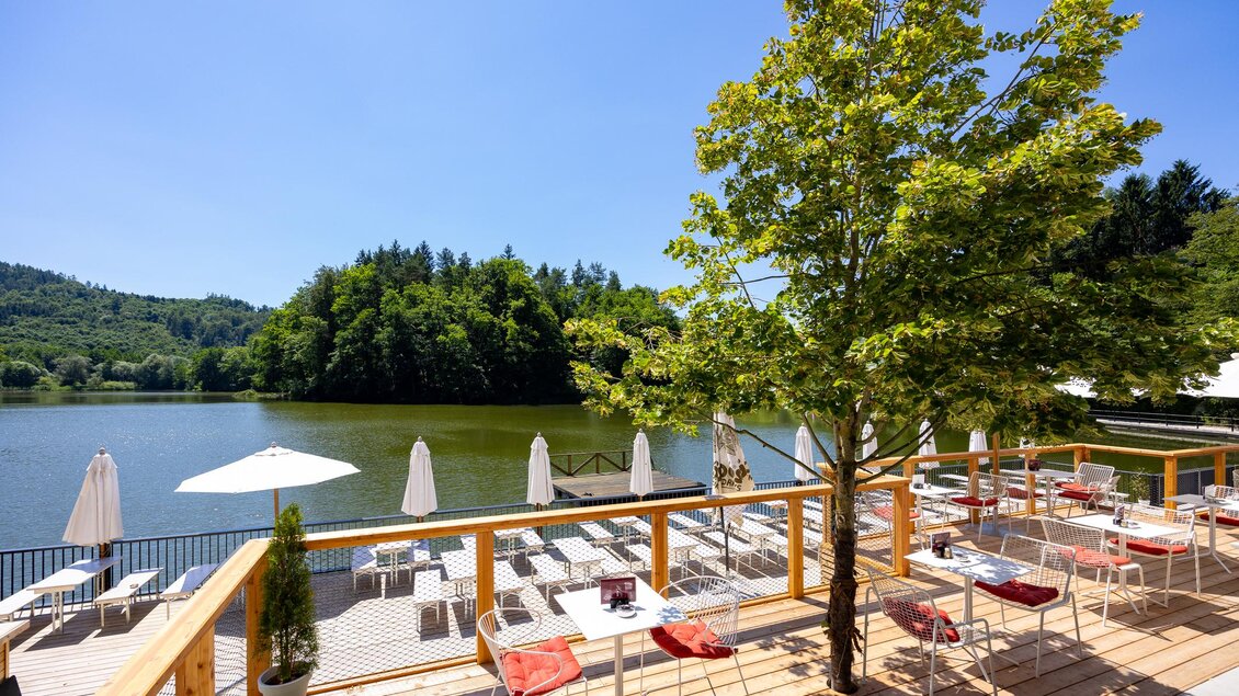 Ein schöner See mit einer Terrasse und Tischen. Umgeben von Bäumen und Sonnenschirmen, bietet der Ort eine entspannte Atmosphäre. | © Region Graz, Harry Schiffer
