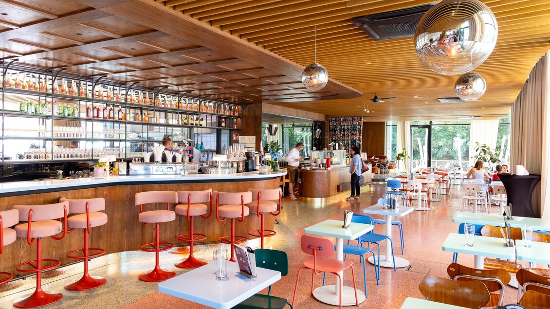 Ein modernes Café mit einer hellen und einladenden Atmosphäre. Bunte Stühle und eine elegante Bar prägen den Raum. | © Region Graz, Harry Schiffer