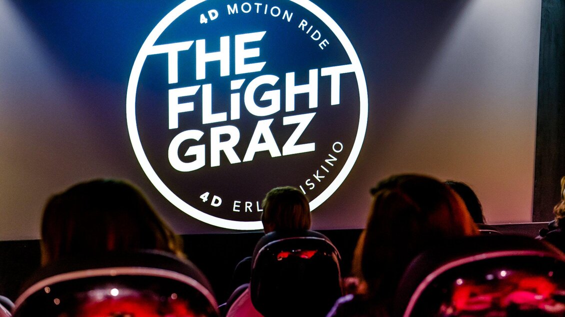 Ein 4D-Motion-Ride namens "The Flight Graz" ist auf der Leinwand zu sehen. Im Vordergrund sind Sitzplätze für die Zuschauer sichtbar. | © Region Graz - Mias Photoart