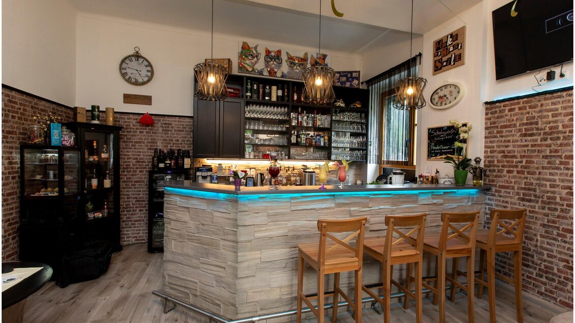 Eine stilvolle Bar mit einer gut sortierten Theke und modernen Beleuchtungselementen. Im Hintergrund sind Nischenregale mit Getränken und Dekoration sichtbar. | © TV Region Graz - Lunghammer