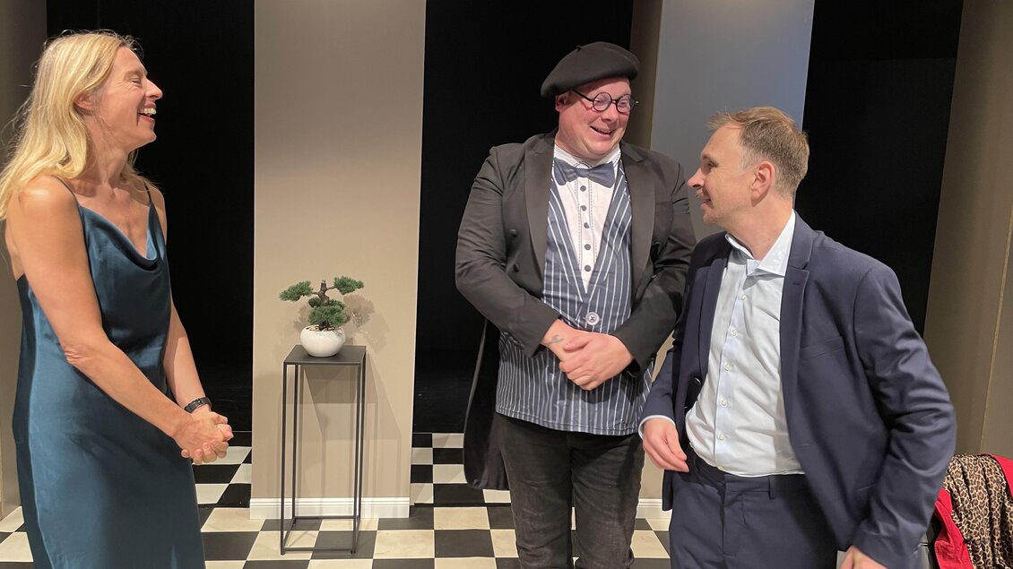Drei Personen stehen in einem geschmackvoll eingerichteten Raum. Sie lachen und unterhalten sich in entspannter Atmosphäre. | © THEO Studiobühne