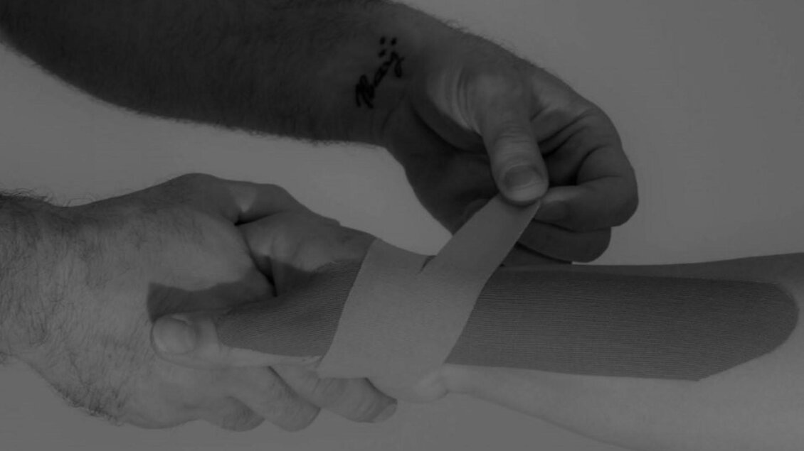 Eine Hand wickelt ein Verband um den Arm einer anderen Person. Die Szene zeigt Erste-Hilfe-Maßnahmen in Aktion. | © Therapiezentrum Prä-Fit