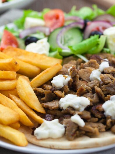 Ein Teller mit saftigem Fleisch, Pommes frites und einem frischen Salat. Dazu gibt es eine cremige Sauce. | © Tinos