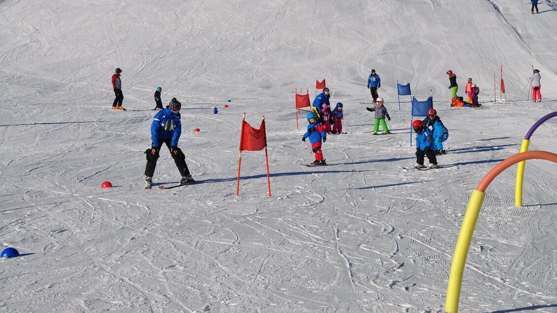 Eine Gruppe von Kindern und Erwachsenen übt Skifahren auf einem schneebedeckten Hang. Bunte Hindernisse und Tore sind auf der Piste aufgestellt. | © Tourismusverband Murau