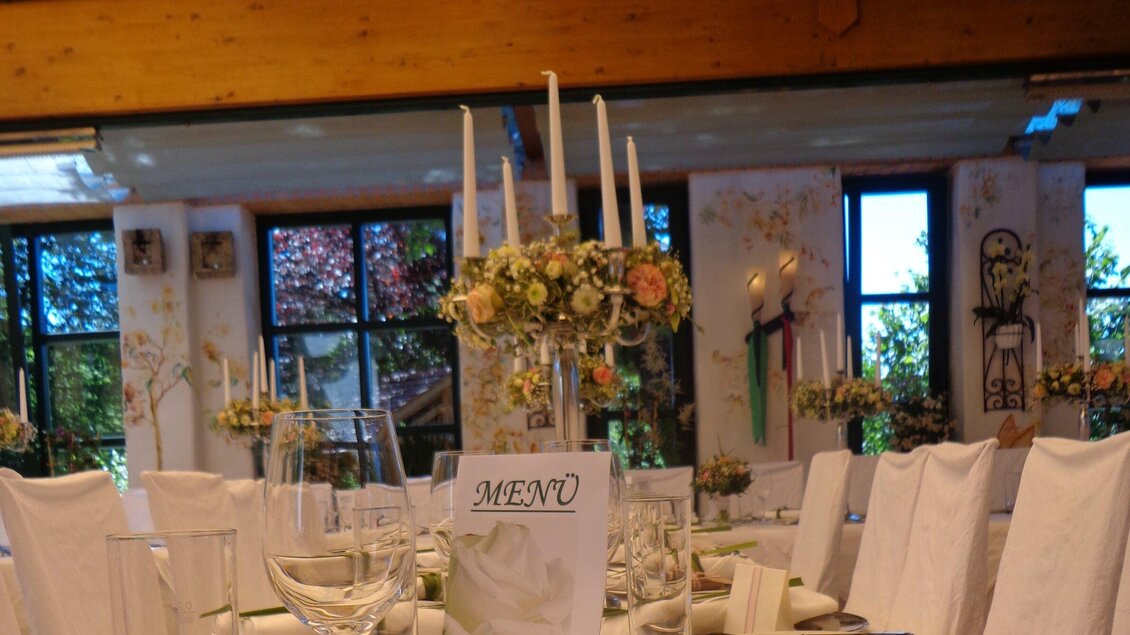 Ein elegant dekorierter Tisch für eine Veranstaltung mit Kerzen und Blumenarrangements. Das Menü ist sichtbar auf einem der Tische. | © Legenstein