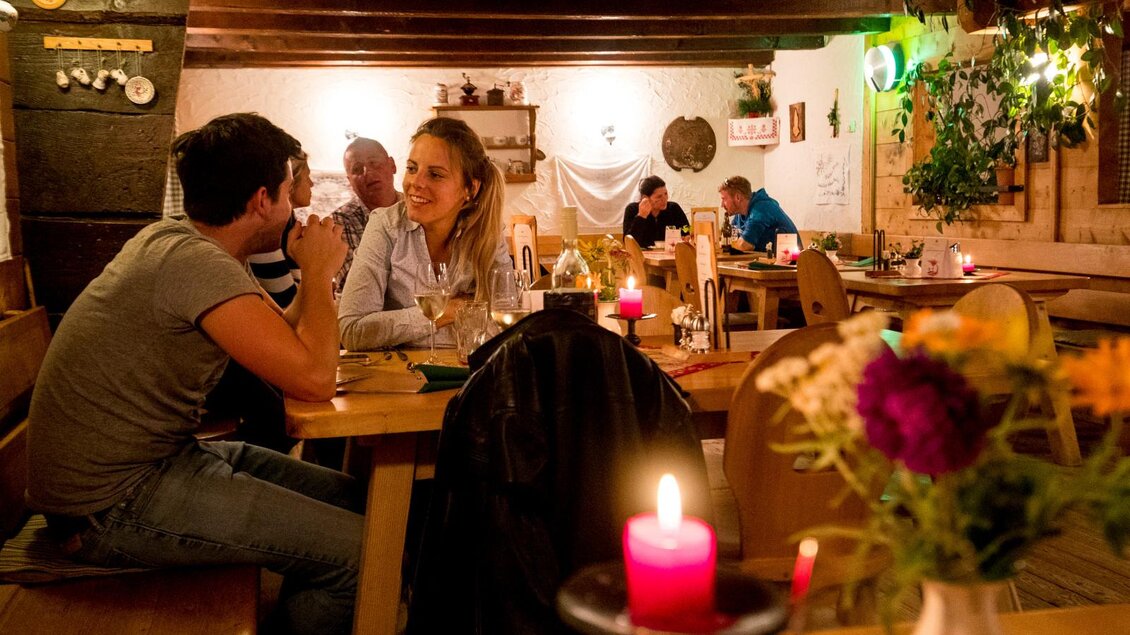 Ein gemütliches Restaurant mit rustikaler Dekoration. Zwei Gäste unterhalten sich an einem Tisch, umgeben von Kerzenlicht und Pflanzen. | © Tourismusverband Murau