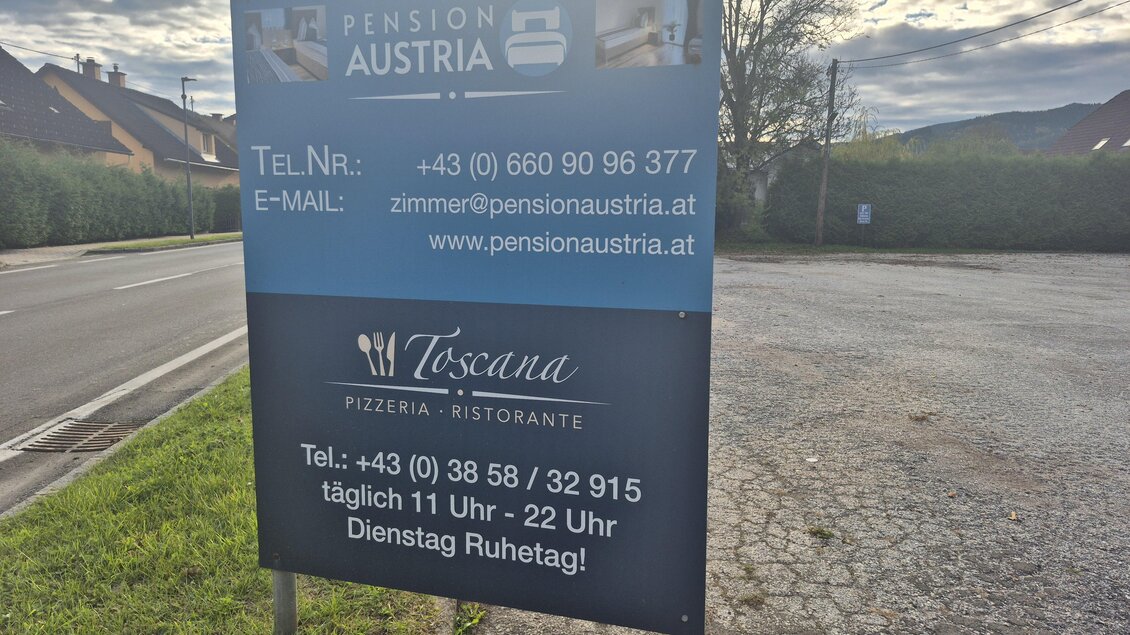 Ein Wegweiserschild für die Pension Austria und die Pizzeria Toscana. Es enthält Kontaktinformationen und Öffnungszeiten. | © TV Hochsteiermark