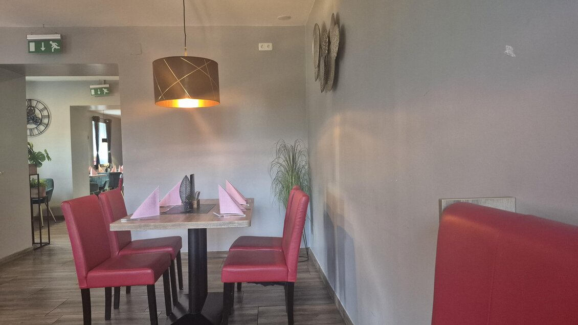 Ein gemütliches Restaurant mit rotem Sitzmöbeln und einem Tisch in der Mitte. Die Wände sind in einem neutralen Farbton gehalten, und eine Pendelleuchte beleuchtet den Raum. | © TV Hochsteiermark
