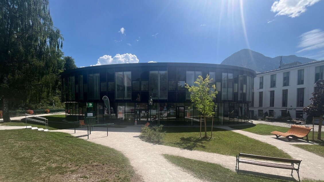 Ein modernes Gebäude mit einer runden Form und großen Fenstern. Umgeben von einer grünen Landschaft und Sonnenlicht. | © TVB Ausseerland Salzkammergut/Gabi Grill