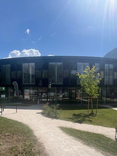 A modern building with a round shape and large windows. Surrounded by a green landscape and sunlight. | © TVB Ausseerland Salzkammergut/Gabi Grill